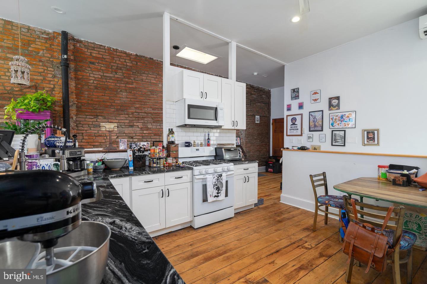 519 South 5th Street Philadelphia, PA 19147 - Photo 15 of 17 a kitchen with stainless steel appliances granite countertop a stove top oven a sink a dining table and chairs with wooden floor