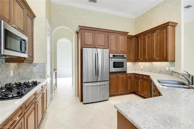 a kitchen with stainless steel appliances granite countertop a refrigerator a stove and a sink with wooden cabinets