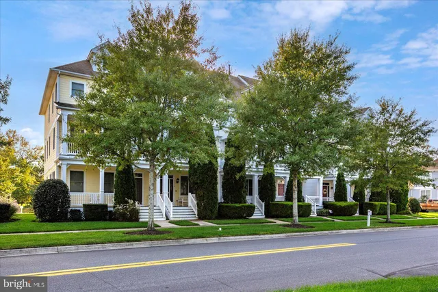 a view of a white house in a big yard with palm trees