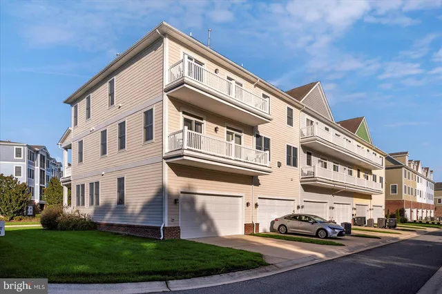 a front view of a building with a garden and parking space