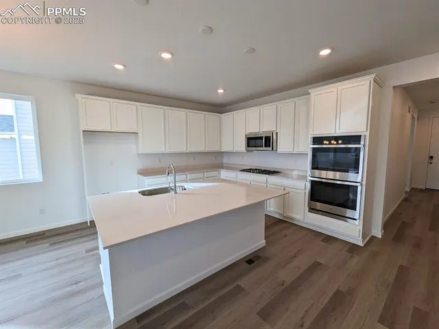 a large white kitchen with wooden floors and center island