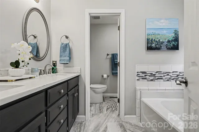 a spacious bathroom with a granite countertop sink a toilet and a mirror