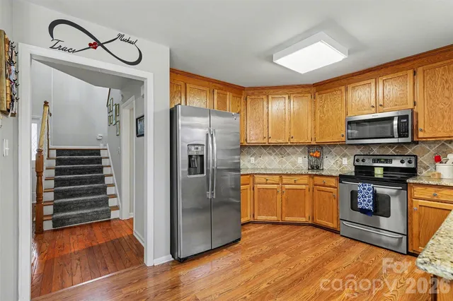 a kitchen with stainless steel appliances granite countertop a refrigerator a stove top oven a sink and dishwasher