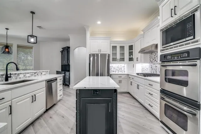 a kitchen with stainless steel appliances kitchen island granite countertop a stove sink and cabinets
