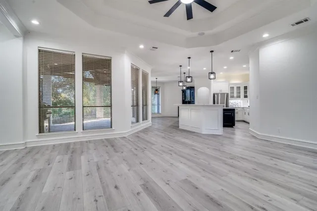 a large white kitchen with wooden floors and stainless steel appliances