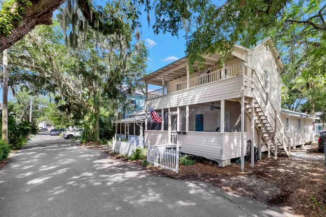 a view of a house with a yard and large tree