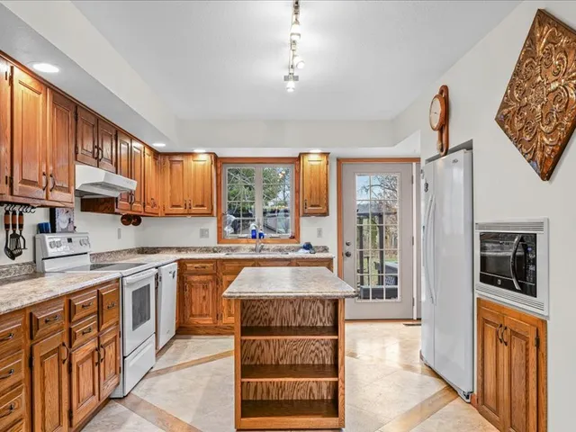a large kitchen with kitchen island granite countertop a large window and a sink