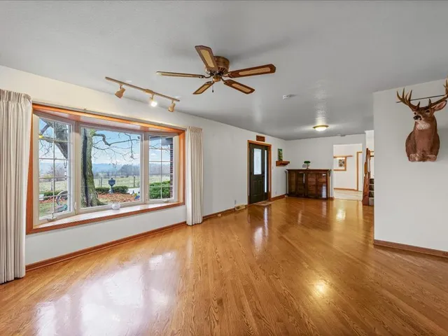 a view of empty room with wooden floor and fan