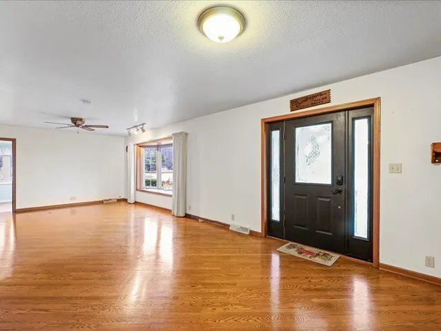 a view of an empty room with window and wooden floor