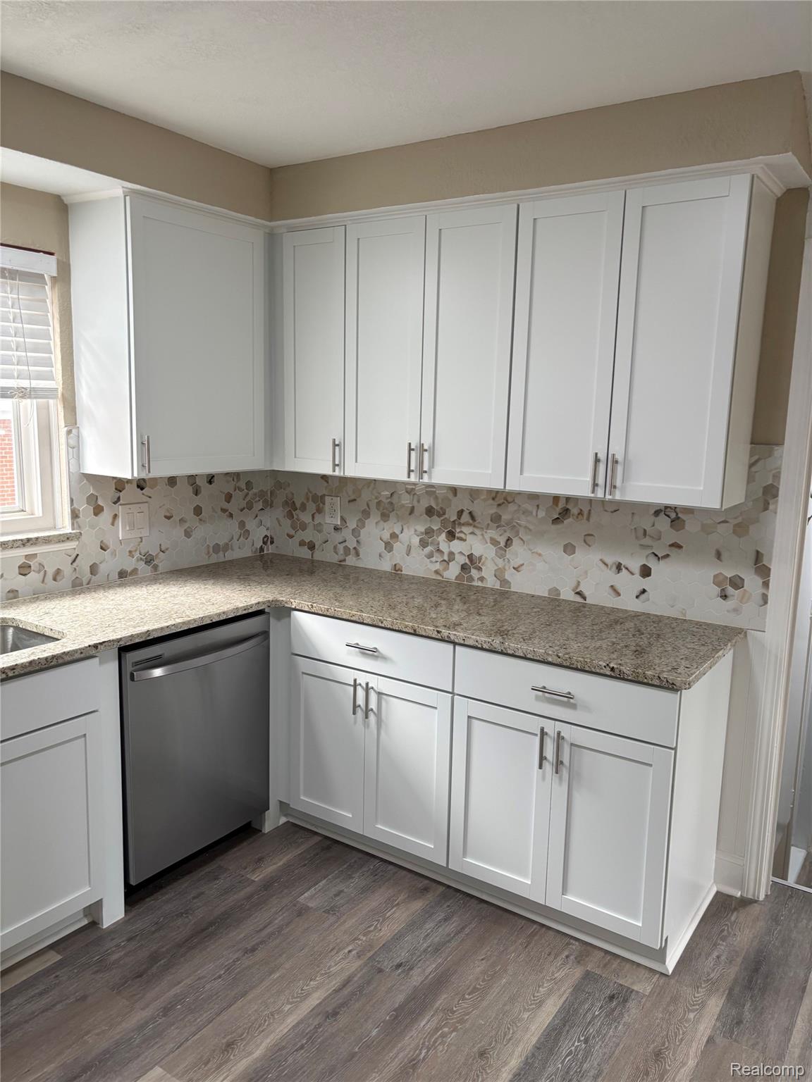 18259 Spring Court South Fraser, MI 48026 - Photo 18 of 60 White shaker-style cabinetry with brushed nickel hardware, granite countertops, stainless steel dishwasher, and wood-finish flooring