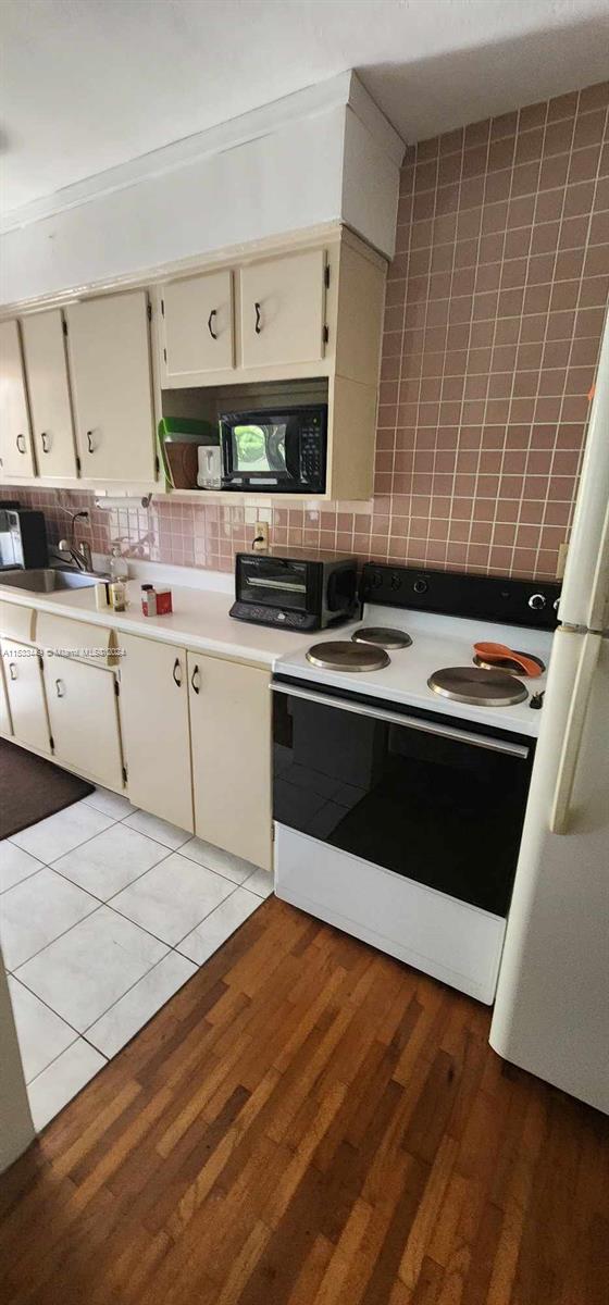 60 Northwest 79th Street, Unit 28 Miami, FL 33150 - Photo 24 of 28 a kitchen with cabinets and wooden floor