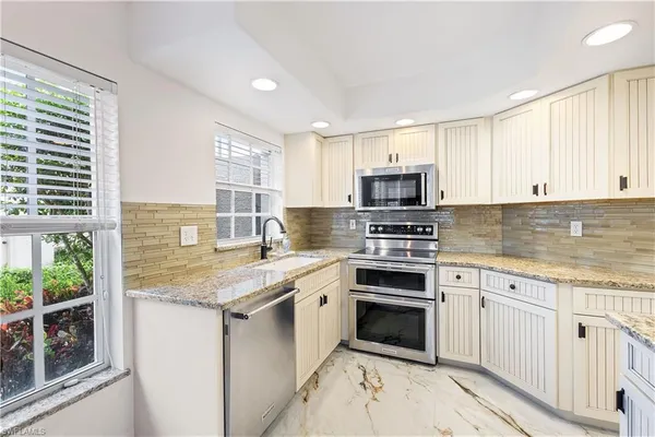 a kitchen with granite countertop a stove sink and microwave