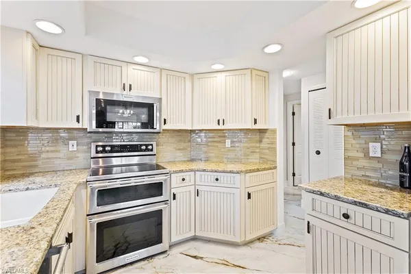 a kitchen with kitchen island granite countertop a stove a sink and a microwave