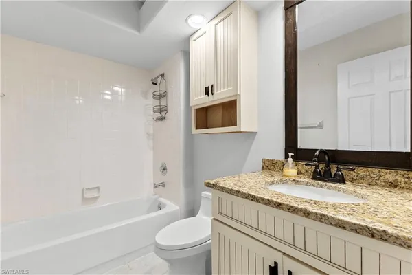 a bathroom with a granite countertop sink a toilet and shower