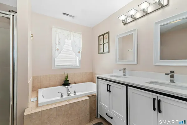 a bathroom with a tub a sink and mirror