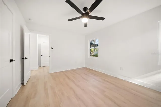 an empty room with ceiling fan and windows