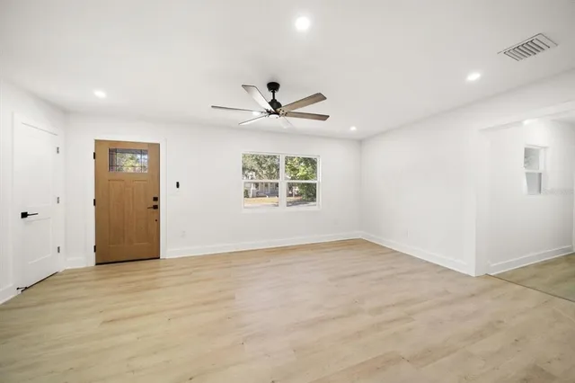 an empty room with windows and ceiling fan