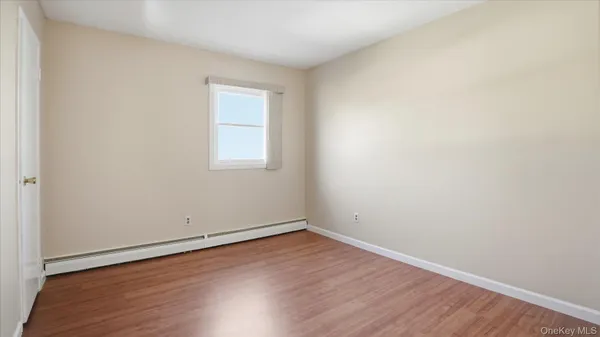 an empty room with wooden floor and window