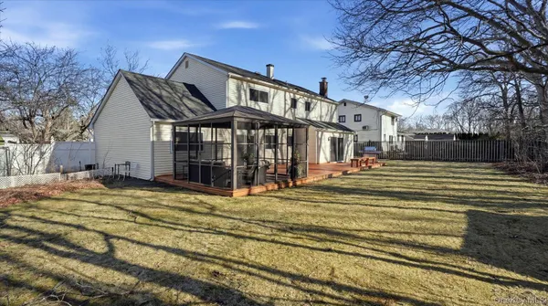 a view of a house with a small yard and large trees