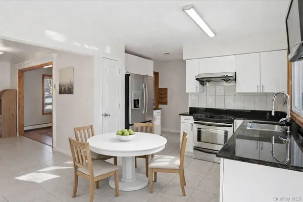 a kitchen with stainless steel appliances a dining table chairs and refrigerator