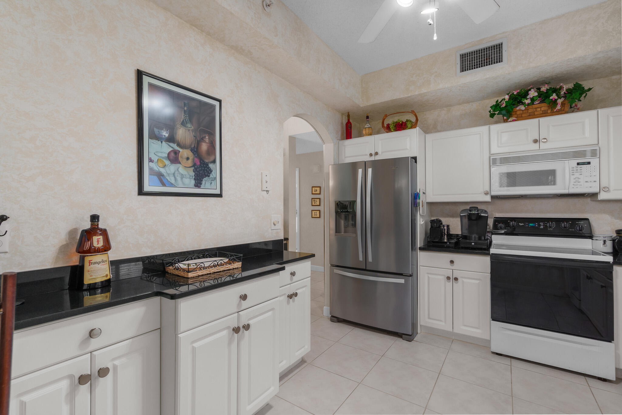 7546 La Paz Boulevard, Unit 405 Boca Raton, FL 33433 - Photo 11 of 43 a kitchen with granite countertop a refrigerator and cabinets