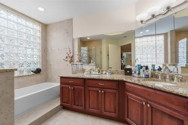 a bathroom with a granite countertop sink mirror bathtub and double