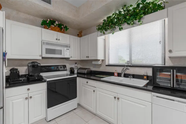 a kitchen with granite countertop white cabinets and white appliances