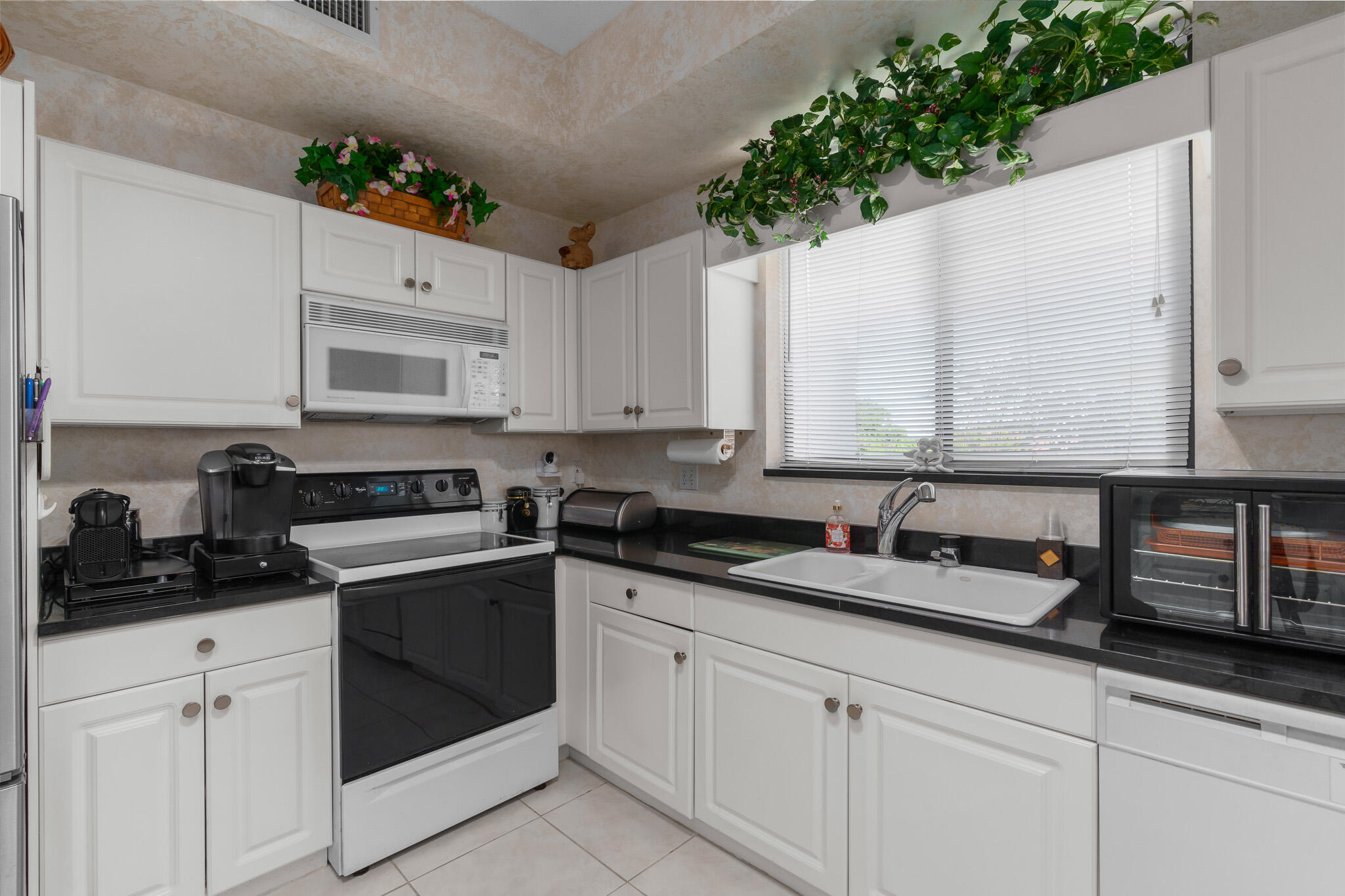 7546 La Paz Boulevard, Unit 405 Boca Raton, FL 33433 - Photo 10 of 43 a kitchen with granite countertop white cabinets and white appliances
