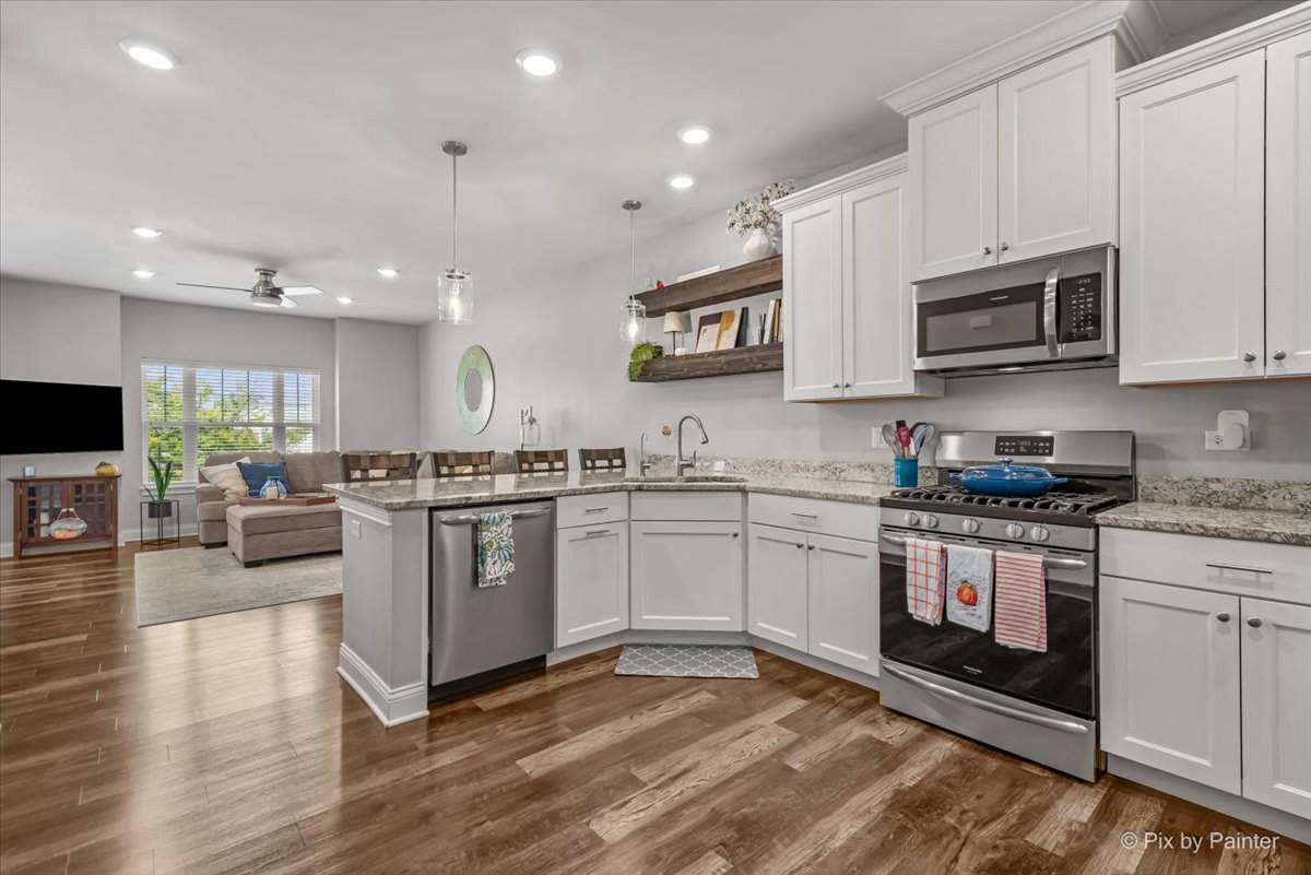 745 Harper Avenue Cary, IL 60013 - Photo 6 of 32 a kitchen with stainless steel appliances granite countertop a refrigerator a stove top oven a sink dishwasher and white cabinets with wooden floor