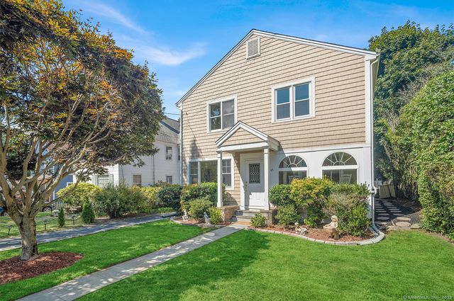 a front view of a house with a yard and trees