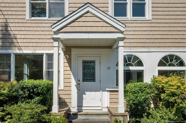 a view of a white house with large windows and potted plants