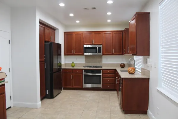 a kitchen with stainless steel appliances granite countertop wooden cabinets a stove a sink and a refrigerator