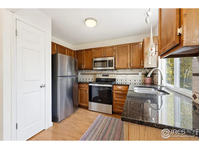 a kitchen with granite countertop wooden cabinets a stove top oven and stainless steel appliances