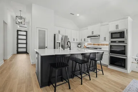 a dining room with stainless steel appliances kitchen island granite countertop a table chairs and a refrigerator