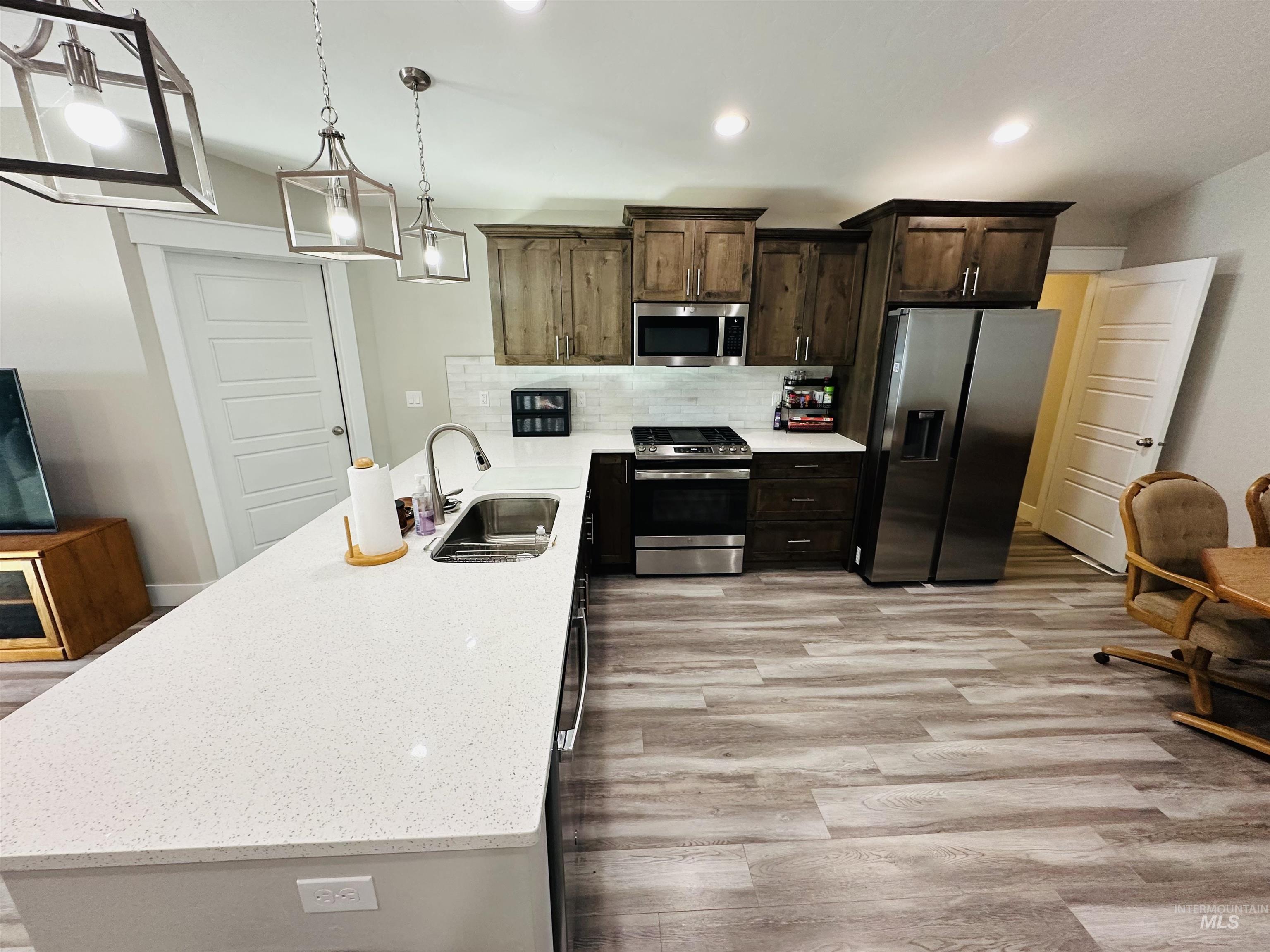 911 Campbell Street Vale, OR 97918 - Photo 3 of 37 Kitchen with appliances with stainless steel finishes, backsplash, a peninsula, light stone countertops, and dark brown cabinets