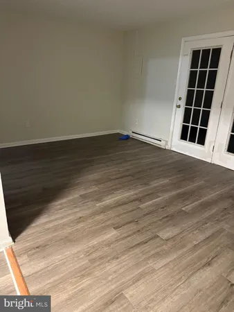 a view of an empty room with wooden floor and windows