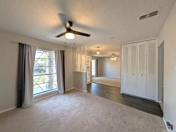 a view of empty room with wooden floor and fan