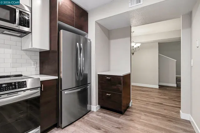 a kitchen with stainless steel appliances and wooden floor