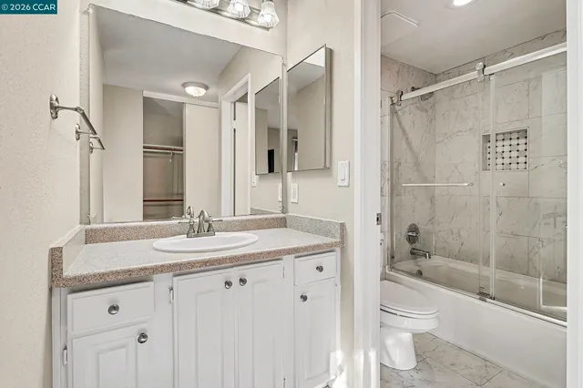 a bathroom with a granite countertop sink toilet and shower