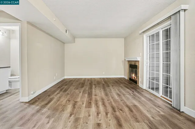 an empty room with wooden floor a fireplace and windows