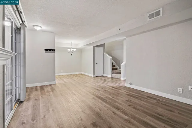a view of empty room with wooden floor and entryway