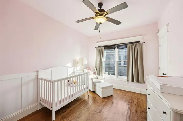 a view of a bedroom with wooden floor and a ceiling fan