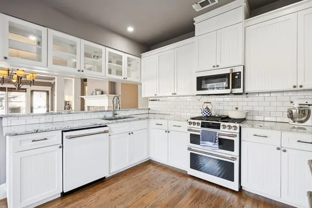 a kitchen with stainless steel appliances granite countertop white cabinets a sink a stove a microwave and cabinetry