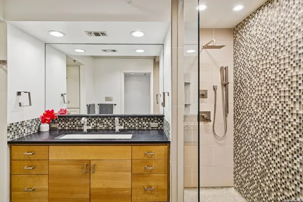 a bathroom with a granite countertop shower a sink and a mirror