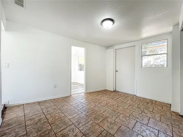 a view of a kitchen and an empty room with a window