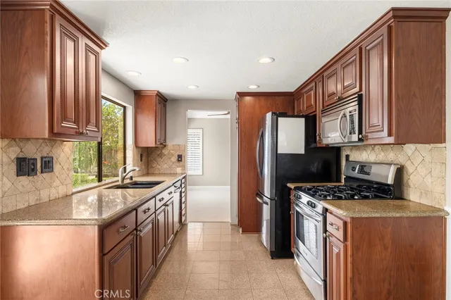 a kitchen with stainless steel appliances granite countertop a stove a sink a refrigerator and a microwave
