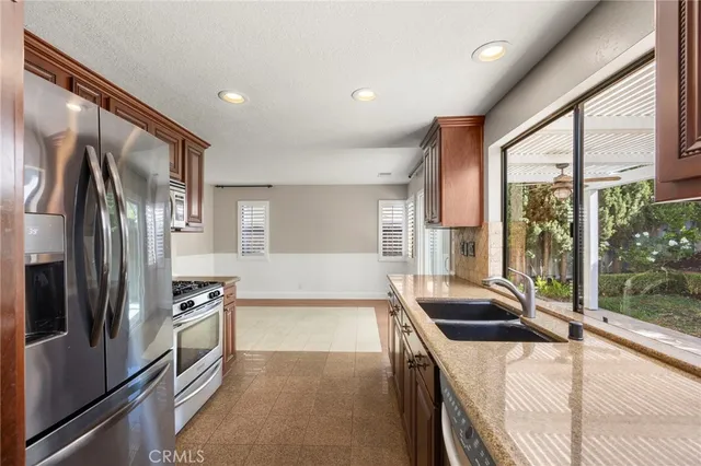 a kitchen with stainless steel appliances granite countertop a sink and a refrigerator