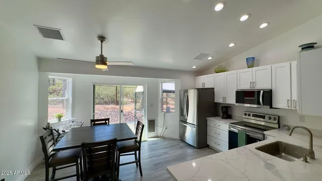 a kitchen with stainless steel appliances a table chairs refrigerator and microwave