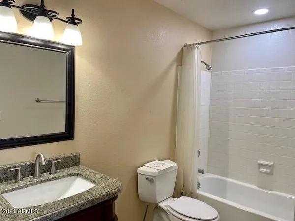 a bathroom with a granite countertop sink toilet a mirror and shower