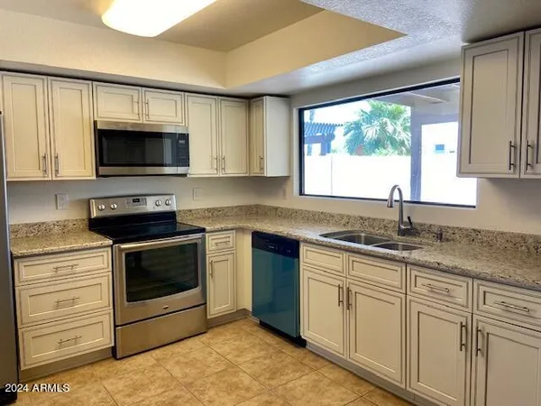 a kitchen with granite countertop a stove sink and microwave